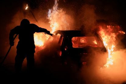 Un bombero apaga las llamas de un coche durante las protestas en Nanterre, la pasada madrugada.  