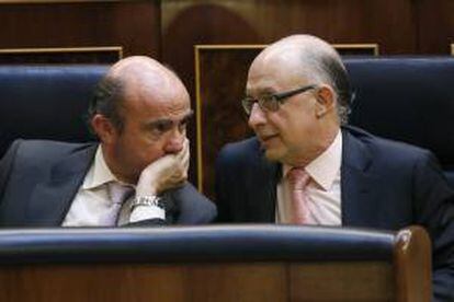 Los ministros de Hacienda, Cristóbal Montoro (d), y de Economía y Competitividad, Luis de Guindos (i), conversan durante un pleno del Congreso de los Diputados. EFE/Archivo