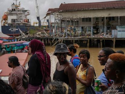 La gente espera en el mercado Stabroek para cruzar el río Demerara en ferry, cerca de un barco portacontenedores en Georgetown, (Guyana)