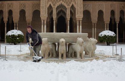 Una encargada del mantenimiento de la fuente de los leones de la Alhambra de Granada retira nieve acumulada después de la intensa nevada.