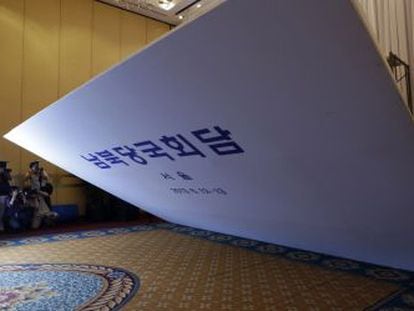 Operarios del Hilton de Se&uacute;l desmantelan un cartel en el lugar de las negociaciones.