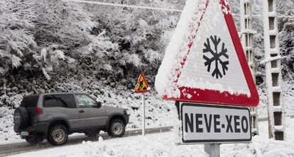 Un autom&oacute;vil circula por una carretera nevada de Galicia.