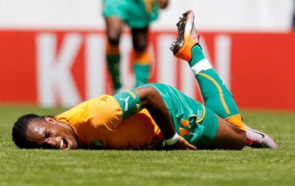 Didier Drogba se duele en el suelo tras chocar con un jugador japonés.