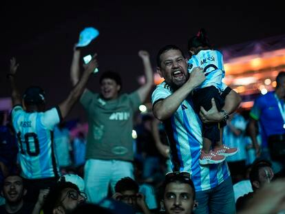 Un hombre, con su hija en manos, celebra el gol de Messi en las afueras del estadio Lusail, en Doha.