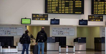 Dos pasajeros comprueban sus vuelos en el aeropuerto vacío de Menorca, en Mahón, este jueves.