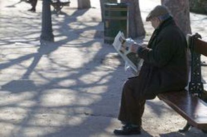 Un anciano lee el periódico en un parque de Madrid.