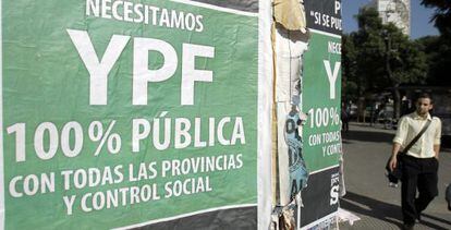 Un hombre pasa frente a varios carteles en los que se pide la estatización de YPF.