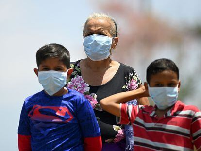 Una mujer y dos niños con mascarilla en Jiquilisco, municipio de El Salvador.