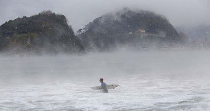 Un surfista se adentra en la playa de Ondarreta, en San Sebastián, en medio de un temporal de frío y nieve.