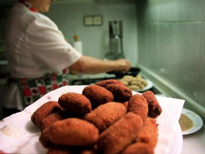 Una mujer cocina croquetas.