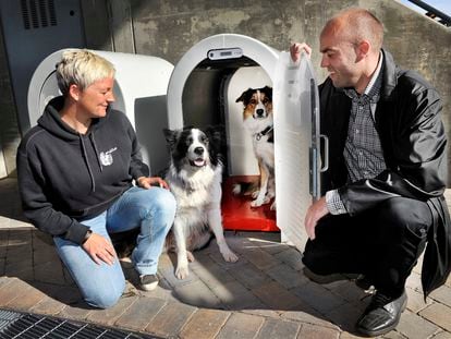 Dos personas muestran una de las casetas de la empresa noruega Den4Dogs para dejar al perro de manera segura en la puerta de un supermercado.