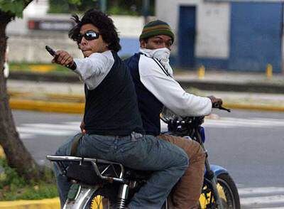 Un joven apunta con una pistola en medio de los disturbios entre estudiantes opositores y chavistas.