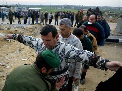 Un policía palestino registra a un trabajador ayer en el paso fronterizo de Erez.