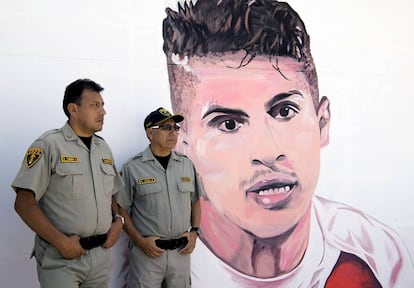 Dos policías delante de un grafiti con el rostro del futbolista Paolo Guerrero, una de las estrellas de la selección de Perú.