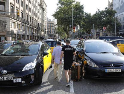 Varios turistas pasan entre los taxis que ocupan la Gran Vía de Barcelona, durante la última huelga del sector.