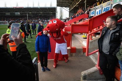 Un joven seguidor posa con Wrex the Dragon, la mascota oficial del Wrexham, durante el descanso del partido ante el Maidenhead United.