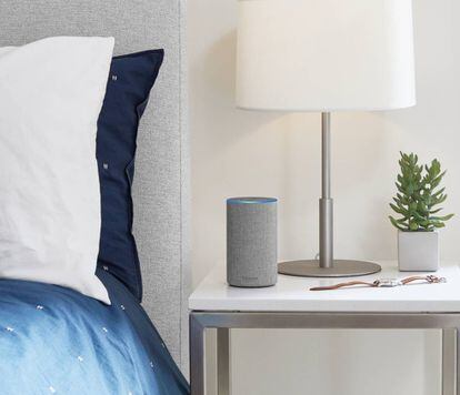 Un altavoz inteligente encima de una mesilla en un dormitorio.