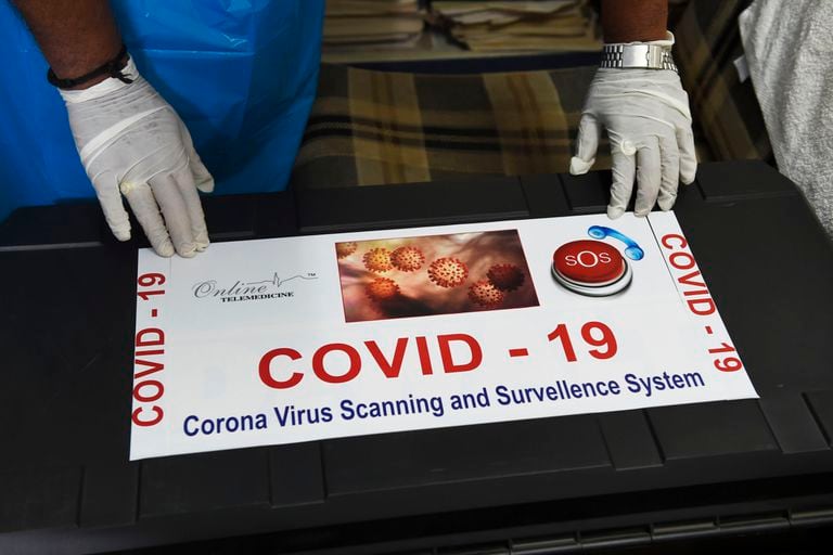 Un miembro del equipo de telemedicina Ragesh Shah en India, antes de un póster sobre el coronavirus.