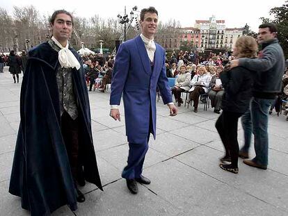Dos figurantes vestidos de época recorren la plaza de Oriente entre los asistentes a las funciones de ópera en la calle.