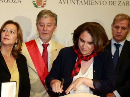Colau firma en el Libro de Oro de Zaragoza el sábado. Detrás de ella, con la banda, Pedro Santisteve, alcalde de la ciudad.