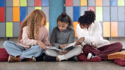 Tres jóvenes analizan un libro.