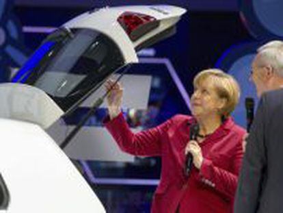 La canciller alemana, Angela Merkel (i), y el presidente de Daimler, Dieter Zetsche, junto a un modelo el&eacute;ctrico de Volkswagen e-Golf, durante la inauguraci&oacute;n del Sal&oacute;n del Autom&oacute;vil de Fr&aacute;ncfort (Alemania).