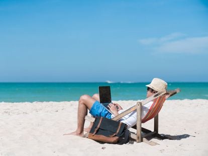 Una persona trabaja desde la playa con su ordenador.
