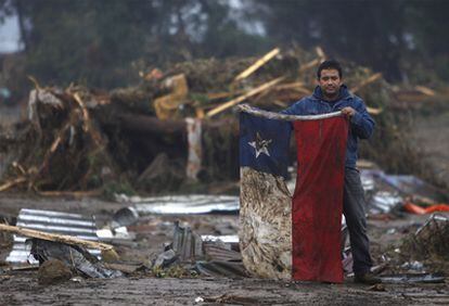 Un habitante de  Pelluhue, a unos 322 kilómetros al sureste de Santiago, muestra una enseña nacional chilena rescatada de los escombros.