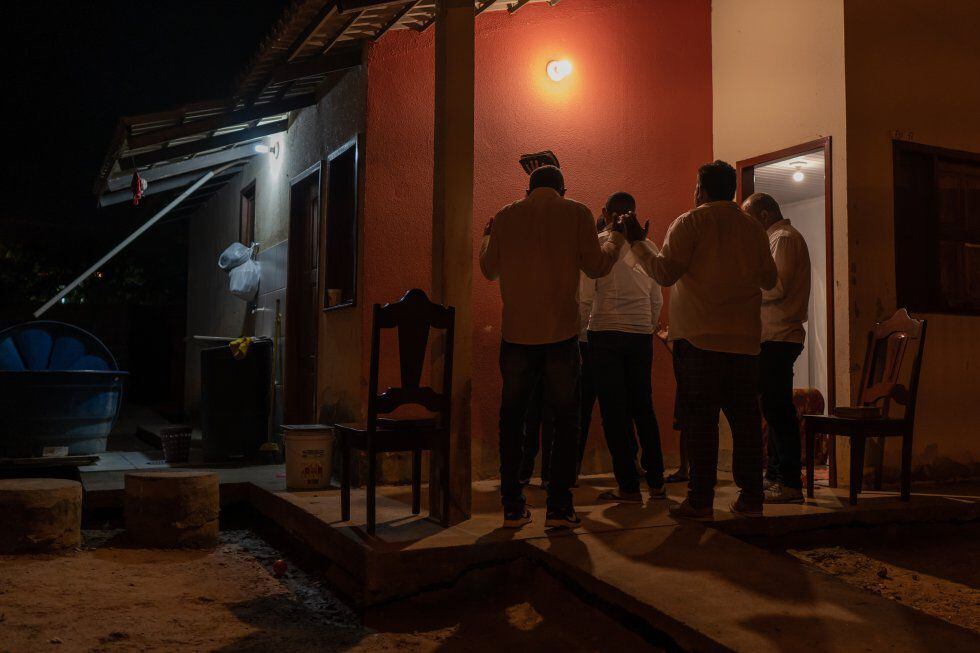 Un grupo de hombres rezan afuera de una casa en Acre, Brasil.