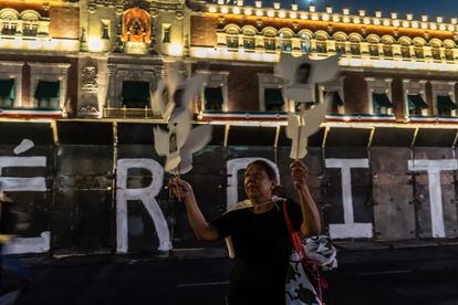 Una mujer lleva palomas blancas y fotografías de los normalistas, durante la manifestación en el Zócalo de Ciudad de México.
