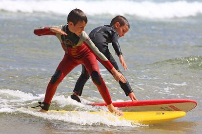 Dos ni&ntilde;os surfeando durante un campamento en la playa de Somo (Cantabria).