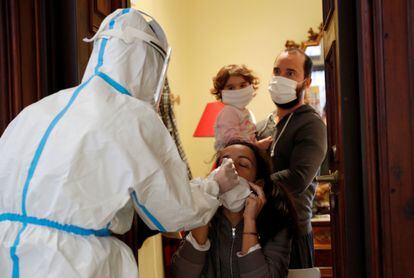 Un sanitario toma muestras para la prueba de la covid a una familia en su vivienda de Roma (Italia).