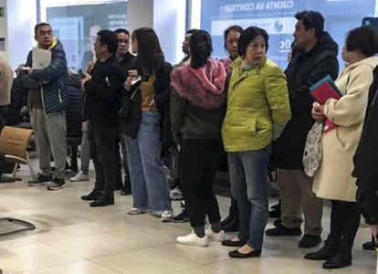 Chinos afectados por los bloqueos de cuentas hacen cola en una sucursal del BBVA en Usera, Madrid.
