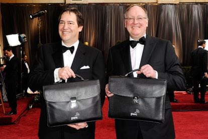 Dos empleados de la consultora PriceWaterhouse Coopers llegan con sendos maletines que contienen los premios.