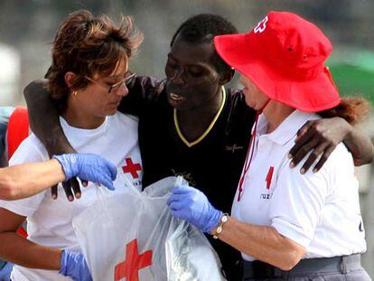 Miembros de la Cruz Roja ayudan a uno de los 90 inmigrantes que llegaron ayer a la playa de los Cristianos (Tenerife).