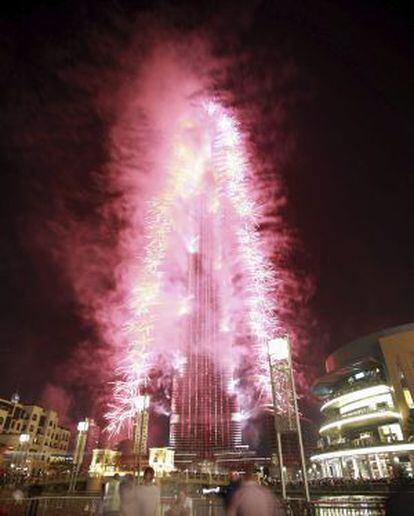 Varias personas observan los fuegos articiales para celebrar que Dubai fue elegida sede para acoger la Exposición Universal en 2020, frente al edificio Burj Khalifa, Dubai, Emiratos Árabes.