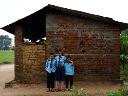Parwati Sunar, 27, and her sons, Resham Sunar, 11, and Arjun Sunar, 7, pose for a picture after getting dressed for school, outside their house in Punarbas, Kanchanpur district, southwest Nepal, August 7, 2022. Parwati attends the same school as her eldest son, Resham, after returning to an education system she fled at the age of 15, when she eloped with a man seven years her senior. Parwaiti  said she hoped to become "literate enough"?to be able to keep household accounts. "I think I should not have left my school," she said, explaining the desire to catch up on the lessons she missed.  REUTERS/Navesh Chitrakar    SEARCH "CHITRAKAR NEPAL EDUCATION" FOR THIS STORY. SEARCH "WIDER IMAGE" FOR ALL STORIES.