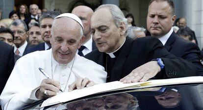 El Papa, junto a mose&ntilde;or Marcelo Sanchez Sorondo, firma un documento en el Vaticano.