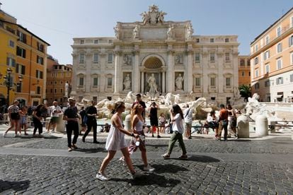 Varias personas caminan frente a la Fontana di Trevi en Roma a fines de junio.
