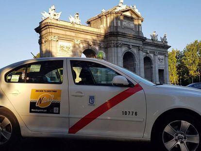 Un taxi agrupado en Ntaxi circula junto a la Puerta de Alcal&aacute;, en Madrid.