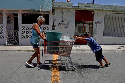 Alma Limón y su nieto, empujan contenedores de agua no potable en un carro de supermercado, durante la sequía de julio 2022 en Apodaca (Nuevo León).