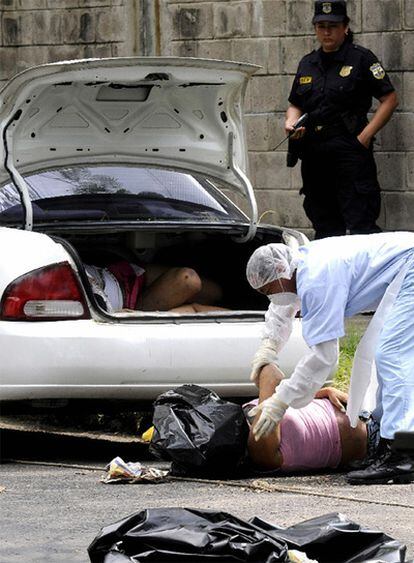 Técnicos de la policía sacan los cadáveres de las cuatro personas asesinadas y halladas en un auto el lunes.