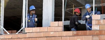 Tres obreros trabajan en la construcción de una vivienda.
