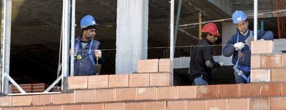 Tres obreros trabajan en la construcci&oacute;n de una vivienda. 