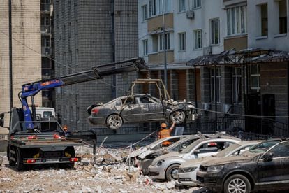 Trabajadores del Ayuntamiento de Kiev retiran varios coches destrozados por los ataques con drones sufridos por la capital de Ucrania la madrugada de este martes.