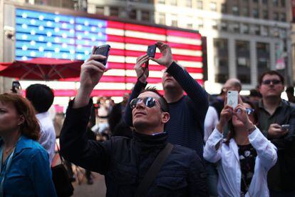 Viandantes en Times Square fotografían el momento de la salida de Facebook en la bolsa.