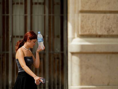 Una mujer caminaba el 10 de agosto en Valencia con una botella de agua fría.