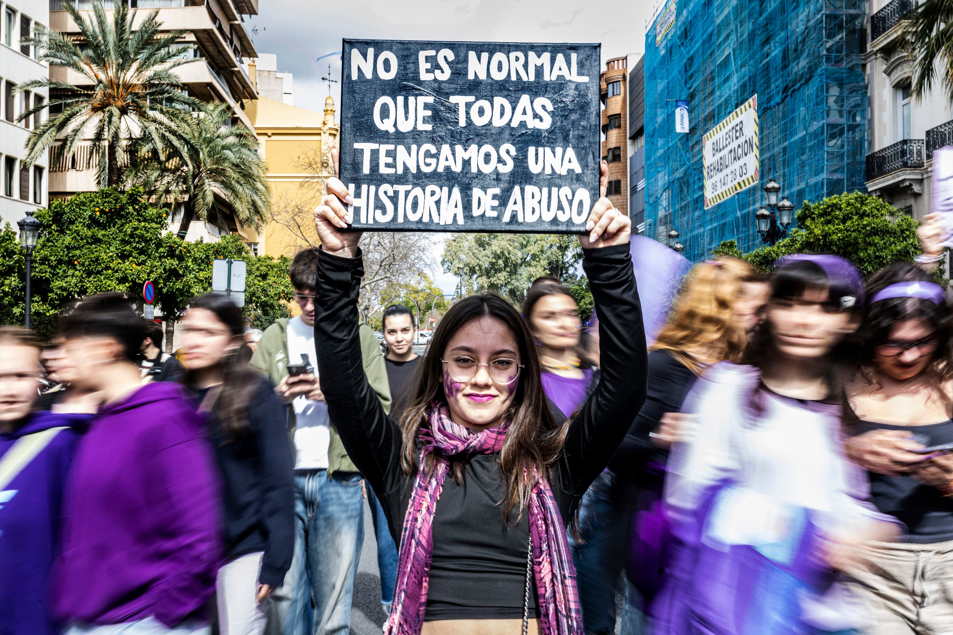 Una joven sostiene un cartel con el lema 