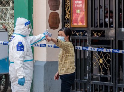 A security guard dressed in protective gear orders a woman to go home for quarantine in Shanghai on Tuesday.