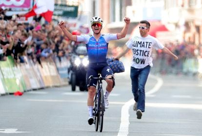 Evenepoel cruza ganador la meta de la Lieja-Bastogne-Lieja ante un activista contra el cambio climático.
